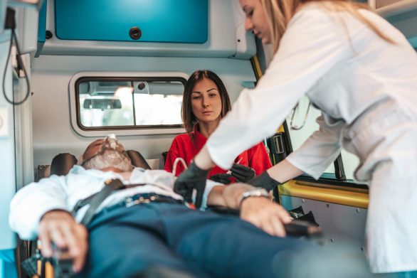 Emergency medical service at work. Paramedic is pulling stretcher with senior man with serious heart attack to the ambulance car. Help on the road. Drivers assistance concept.